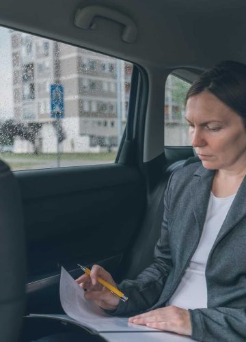 businesswoman-doing-business-paperwork-on-car-back-seat.jpg